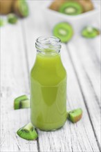 Wooden table with fresh made Kiwi Smoothie (close-up shot, selective focus)