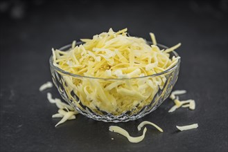 Homemade Grated Cheese (close-up shot) on a vintage slate slab