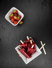 Homemade Strawberry Popsicles (close-up shot, selective focus) on vintage background