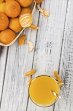 Wooden table with fresh homemade Tangerine Juice (close-up shot, selective focus)