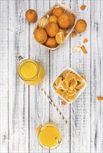 Wooden table with fresh homemade Tangerine Juice (close-up shot, selective focus)