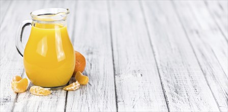 Wooden table with fresh homemade Tangerine Juice (close-up shot, selective focus)