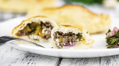 Wooden table with fresh homemade Empanadas (detailed close-up shot, selective focus)