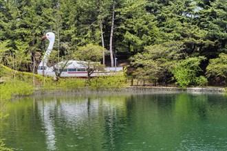 A large swan-shaped boat on a lake surrounded by lush green trees, in Suncheon, South Korea, Asia