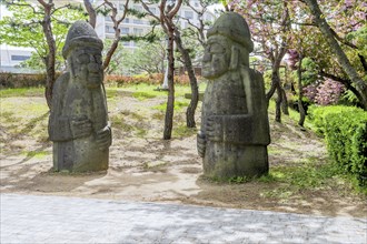 Two large stone statues standing in a park with trees around, in Suncheon, South Korea, Asia