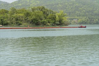 A calm lake with green hills and a boat in the background, in Suncheon, South Korea, Asia