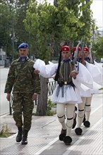 Evzones march on the pavement for the changing of the guard in front of the parliament building,