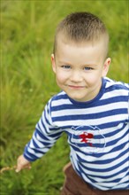 A smiling boy wearing a striped shirt outdoors on a grassy field.Belarus.Minsk