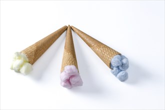 Different colored cotton balls in an ice cream cone isolated on a white background