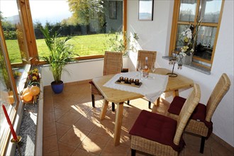 Cosy conservatory as a dining area with wooden table and chairs, surrounded by windows with views