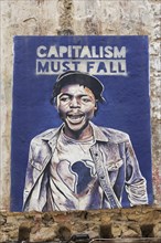 Poster critical of capitalism with a portrait of a coloured man in Exarchia, district of the