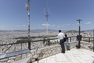 Lycabettus, Lykavittos panoramic terrace, couple looking at city panorama, Athens, Greece, Europe