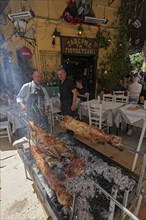 Man grilling lambs on a spit in front of a taverna, Easter lamb, Plaka neighbourhood, Athens,