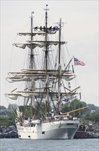 New London, Connecticut, USA, July 2012: Crew members high up in the rigging furl the sails on the