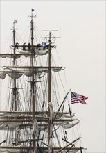 New London, Connecticut, USA, July 2012: Crew members high up in the rigging furl the sails on the