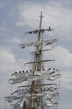 New London, Connecticut, USA, July 2012: Crew members high up in the rigging furl the sails on the