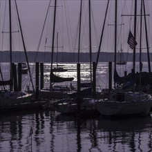 Sailboats in silhouette at anchor with a purple sunrise. Niantic, East Lyme, Connecticut, New