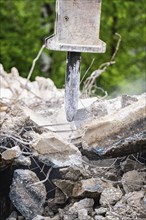 Close-up of an excavator breaking up concrete on the construction site. Debris and dust are