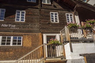 Rustic wooden house with flowers in pots on the stairs and window sills, Saas Fee, Switzerland,