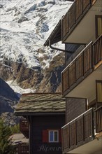 Wooden balconies in a mountain village, with snow-capped mountains in the background, Saas Fee,