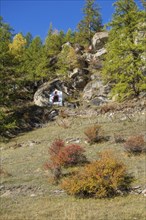 A small chapel nestled in an autumnal, rocky landscape with trees, Saas Fee, Switzerland, Europe