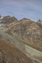 Steep mountains with exposed geological layers under a clear sky, Saas Fee, Switzerland, Europe