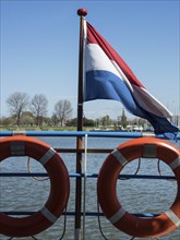 Dutch flag and lifebuoys on a jetty under a clear sky, enkhuizen, the netherlands