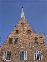 Brick building with a striking gable front and a spire, large windows break up the brick surface,