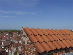 Red tiled roof and brick structure overlooking a historic old town and clear skies, lüneburg,
