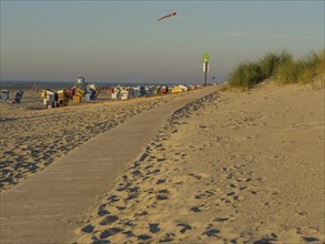 A sandy path on the beach leads past a row of beach chairs and ends in the distance, langeoog,