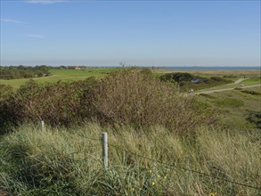 A wide view over the dunes and meadows to the sea, with a clear sky, langeoog, germany