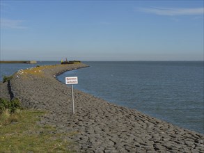 Stony dyke stretches into the sea under a blue sky, langeoog, germany