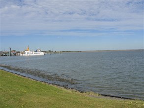 A harbour with a ship and a green meadow next to the sea under a clear sky, langeoog, germany