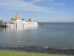 A ferry at the harbour, calm water and a clear blue sky, langeoog, germany