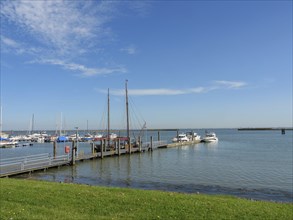 A harbour with several boats and sailboats at the pier under a clear sky, langeoog, germany