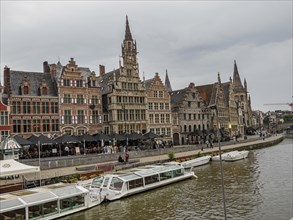 Lively riverside scene with Gothic towers, historic buildings, restaurants and boats, Ghent,