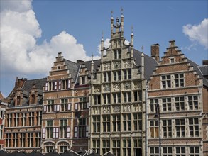 Gabled houses in historic brick style with windows in the sunlight under a blue sky, Ghent,