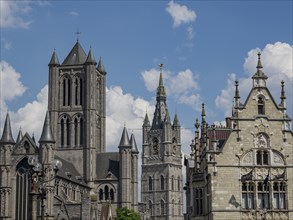 Historic towers and Gothic-style cathedral under a cloudy sky, Ghent, Belgium, Europe