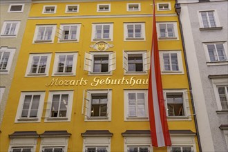 Yellow historical building with the inscription Mozart's birthplace and an Austrian flag, Salzburg,