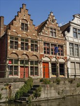 Two historic brick buildings with ornate faÃ§ades along a canal, Ghent, Belgium, Europe