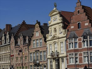 Row of old brick buildings with distinctive gables and window frames on a sunny day, gent, belgium