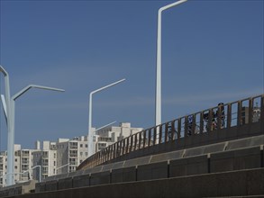 Overpass with railings and cyclists under a clear sky, scheveningen, the netherlands