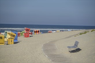 Colourful beach chairs on a sandy beach with a wooden path, quiet atmosphere, langeoog, germany