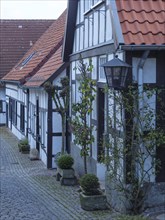 Narrow cobblestone alley with half-timbered houses and lanterns in a historic neighbourhood,