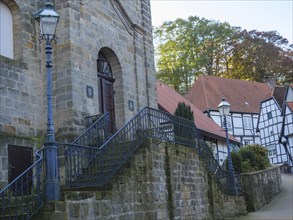 Stone church with banisters, lanterns and half-timbered houses in an autumnal atmosphere,