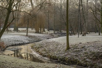 A small stream with a bridge in a frost-covered park landscape in winter morning, Velen, North