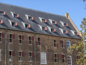 Historic building with many sloping skylights and red shutters under a clear sky, Doesburg,