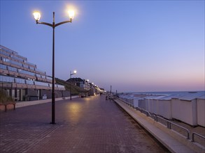 Dusk on a quiet beach promenade with glowing lanterns, de haan, Belgium, Europe