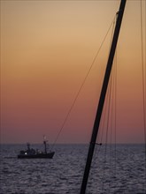 Ferrymen on the horizon, sailing mast in the foreground, atmospheric light and calm atmosphere at