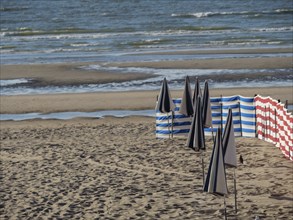 Beach view with blue-white and red-white windbreaks and calm sea in the background, de haan,